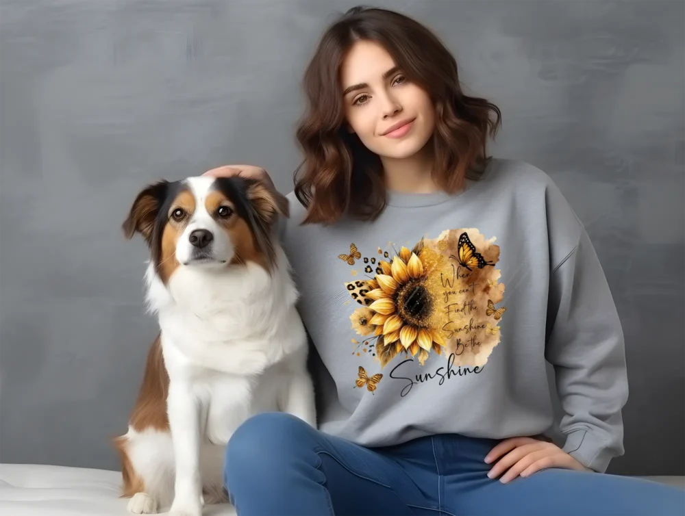 Woman sitting with dog wearing grey sweatshirt with sunflower inspirational quote