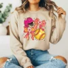 Girl sitting wearing a light brown sweatshirt with a coquette softball design