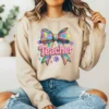 Girl wearing a tan hoodie with a pastel coquette bow graphic