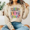 Girl wearing a tan hoodie with a colorful Easter bunny graphic