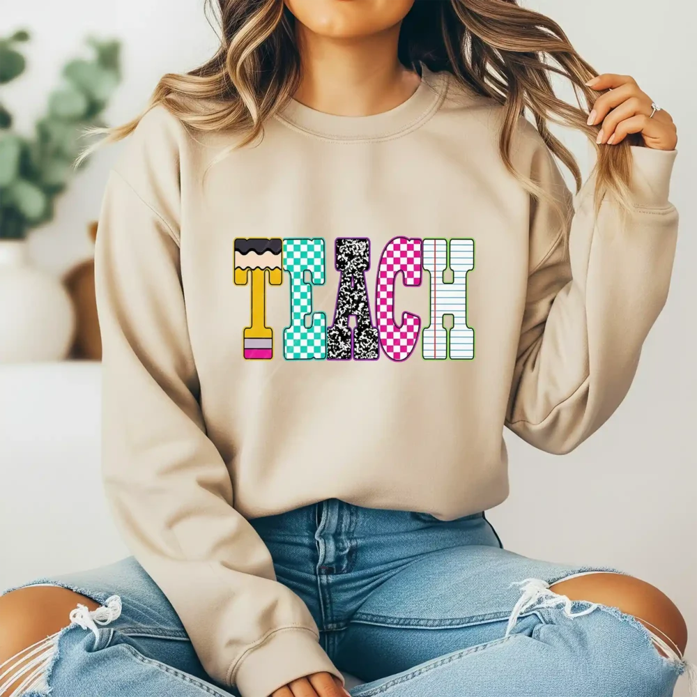 Girl wearing a brown sweatshirt with a retro TEACH design