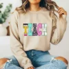 Girl wearing a brown sweatshirt with a retro TEACH design