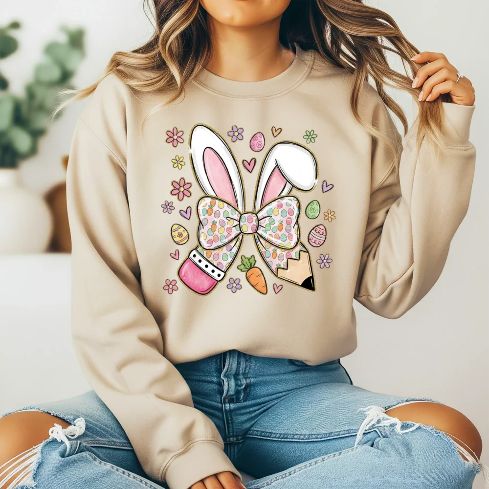 Girl wearing a tan hoodie with a festive pencil bow graphic