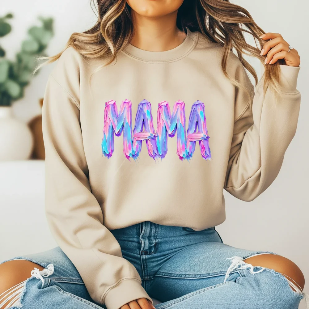 Girl wearing a tan hoodie with a 3D oil paint mama graphic