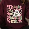 A woman wearing a maroon crewneck sweatshirt with a retro coquette halloween sublimation PNG graphic reading Thanks for not ghosting me with a cute bow ghost and pearls.