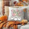 A cozy throw pillow mock-up with a retro halloween sublimation design reading I'm here for the boos, showing three cute ghosts with pastel pink and sage bows in autumn decor.