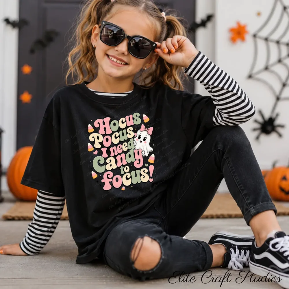 oung girl with pigtails wearing sunglasses and a black layered long-sleeve t-shirt with retro Halloween clipart design printed on the front.