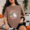 Close-up of a model wearing a brown t-shirt featuring the retro Ghouls Just Want to Have Fun Halloween graphic.