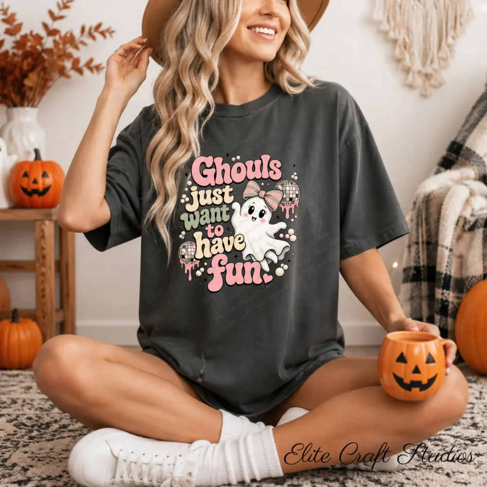 Woman wearing a dark charcoal Halloween t-shirt featuring a cute pink coquette ghost graphic while holding a pumpkin mug.
