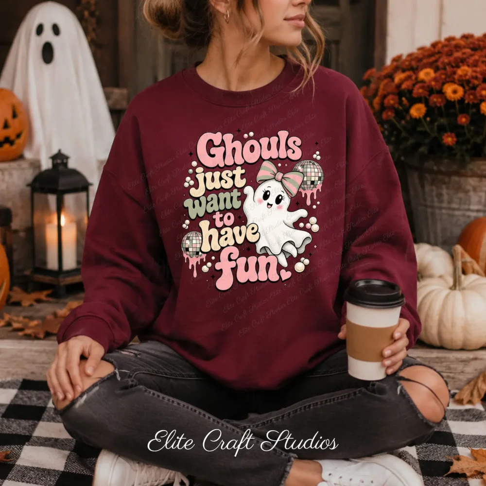 Woman sitting outdoors in a maroon Halloween sweatshirt printed with a pink coquette ghost design and coffee cup.