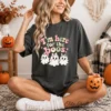 Woman wearing an oversized charcoal t-shirt printed with the spooky cute here for the boos png design.