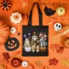 Black canvas tote bag mockup decorated with a steampunk ghost PNG sublimation graphic, surrounded by candy corn, bats, spiders, and autumn leaves on an orange background.