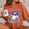Model sitting in bed wearing an orange terracotta t-shirt with the cute ghost design while holding a ghost mug.