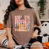 Model seated indoors wearing a brown crewneck shirt printed with the pastel Creepy and Cute Halloween artwork next to a pumpkin mug.