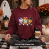 Woman outdoors in a maroon crewneck sweatshirt printed with the kawaii Halloween boxes graphic, holding a coffee cup next to pumpkins.
