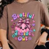 Woman wearing an earth brown t-shirt featuring the Bootiful Inside and Out design with a pink pumpkin and melting lettering.