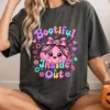 Woman wearing a dark charcoal oversized graphic t-shirt featuring the Bootiful Inside and Out pink pumpkin graphic while holding a pumpkin mug.