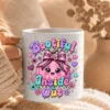 Close-up of hands holding a white ceramic mug sublimated with the Bootiful Inside and Out pink pumpkin illustration, wrapped in a knit blanket.