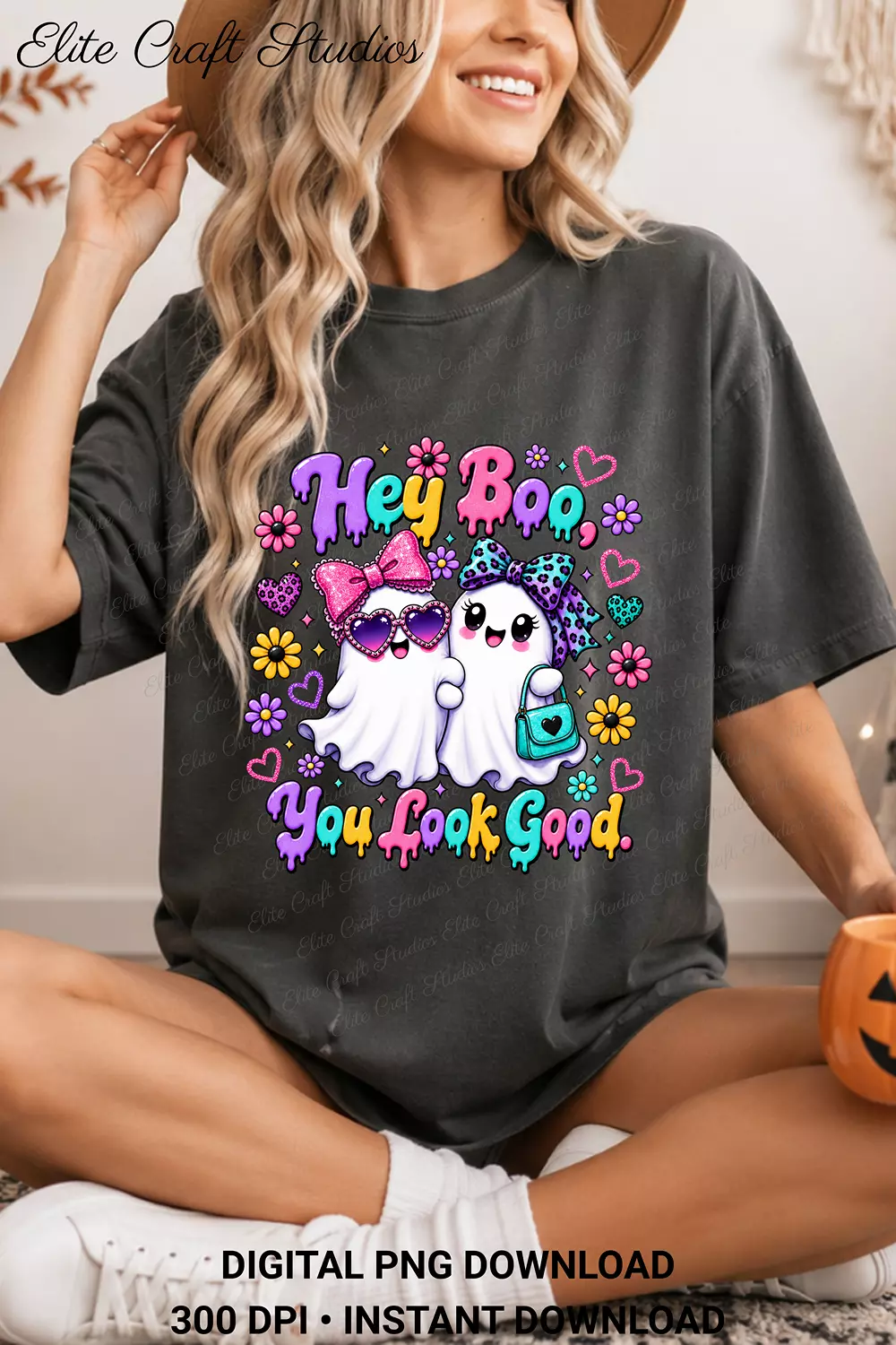 Model seated wearing a dark charcoal oversized t-shirt printed with the colorful Hey Boo ghost illustration.