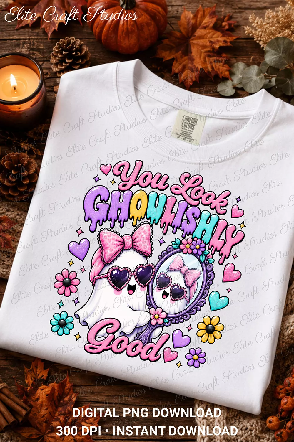 Flat lay mockup of a white t-shirt printed with the You Look Ghoulishly Good ghost design surrounded by fall leaves, pinecones, and a candle.