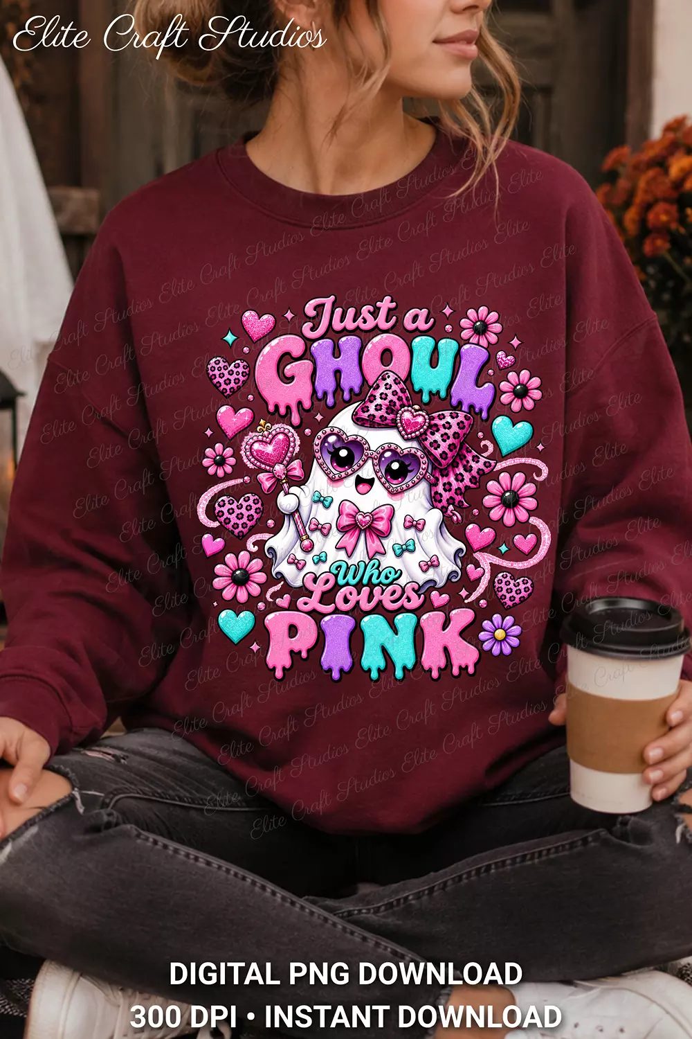 Woman holding a takeaway coffee cup while wearing a maroon crewneck sweatshirt with the Just a Ghoul Who Loves Pink ghost print.