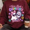 Woman sitting outside wearing a deep maroon sweatshirt printed with the retro pastel ghost graphic while holding a coffee cup.