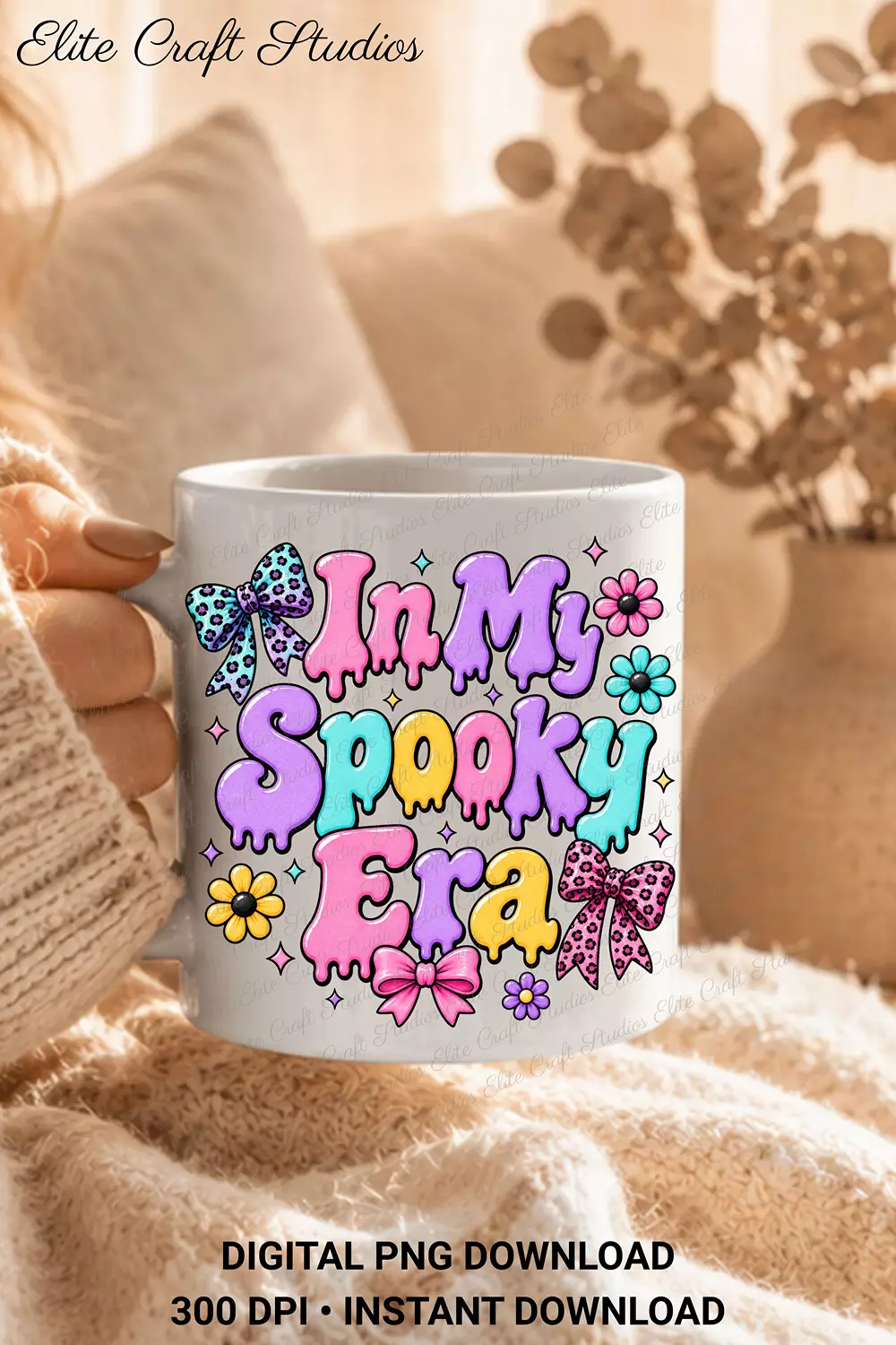 Close-up of hands holding a white ceramic coffee mug printed with the In My Spooky Era pastel dripping graphic wrapped in a cozy knitted blanket.