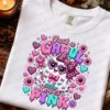 Flat lay mockup of a white Comfort Colors t-shirt printed with the Just a Ghoul Who Loves Pink ghost design, arranged with autumn leaves, pine cones, and a lit candle.