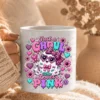 Hand holding a white ceramic coffee mug printed with the Just a Ghoul Who Loves Pink design against a soft neutral knit blanket.