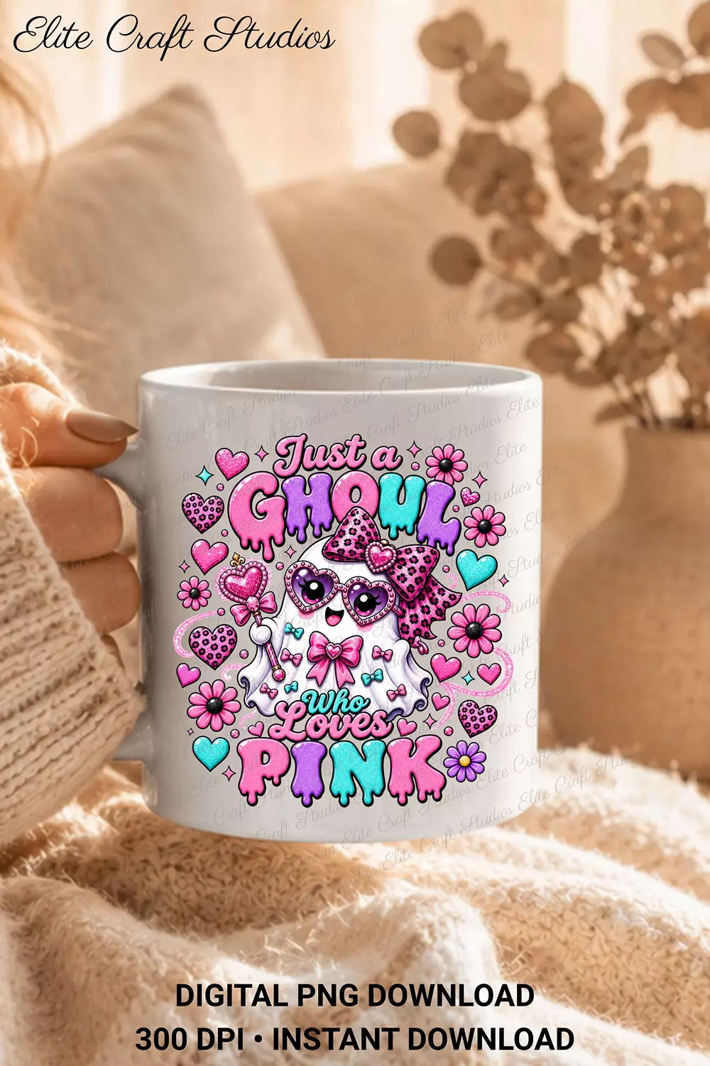 Hand holding a white ceramic coffee mug printed with the Just a Ghoul Who Loves Pink design against a soft neutral knit blanket.