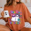 Woman sitting in bed wearing an orange terracotta t-shirt printed with the Hey Boo You Look Good graphic while holding a ghost mug.