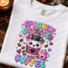 White graphic t-shirt mockup printed with the Spookily Obsessed with Coffee design laid flat surrounded by autumn leaves, pinecones, and a candle.