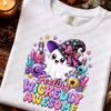 Folded white Comfort Colors t-shirt printed with the Feeling Wickedly Awesome cute ghost design, displayed flat on a dark wood background with fall leaves, pinecones, and a lit candle.
